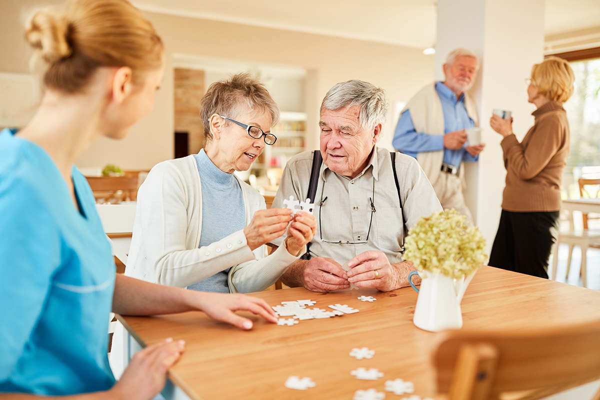 Ältere Personen sitzen gesellig beieinander und puzzlen